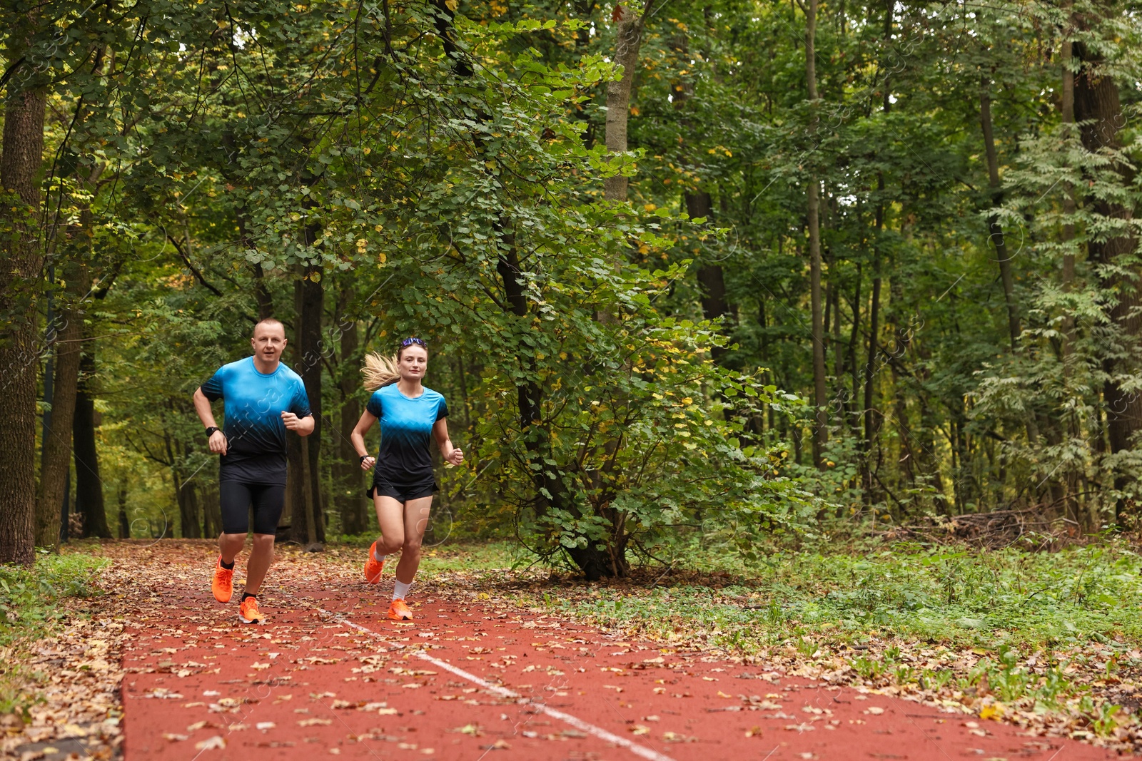 Photo of Athletic man and woman running in park, space for text