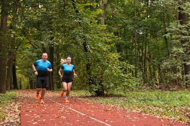 Photo of Athletic man and woman running in park, space for text