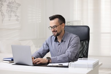 Photo of Smiling banker working with laptop at table in office