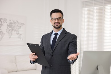 Photo of Smiling banker with clipboard holding something in office