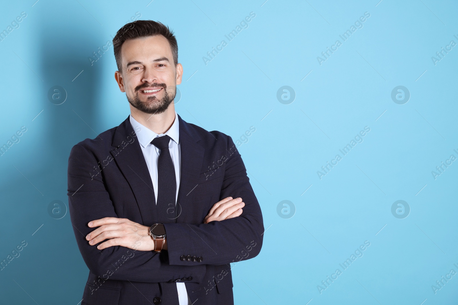 Photo of Portrait of smiling banker with crossed arms on light blue background. Space for text