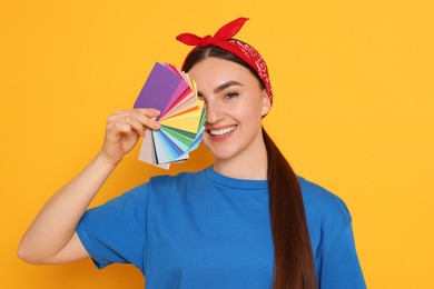 Photo of Portrait of young decorator with color palettes on orange background