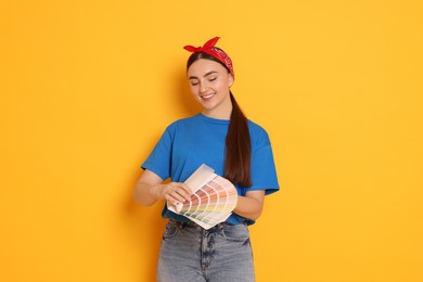 Photo of Portrait of young decorator with color palettes on orange background