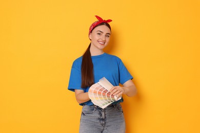 Photo of Portrait of young decorator with color palettes on orange background