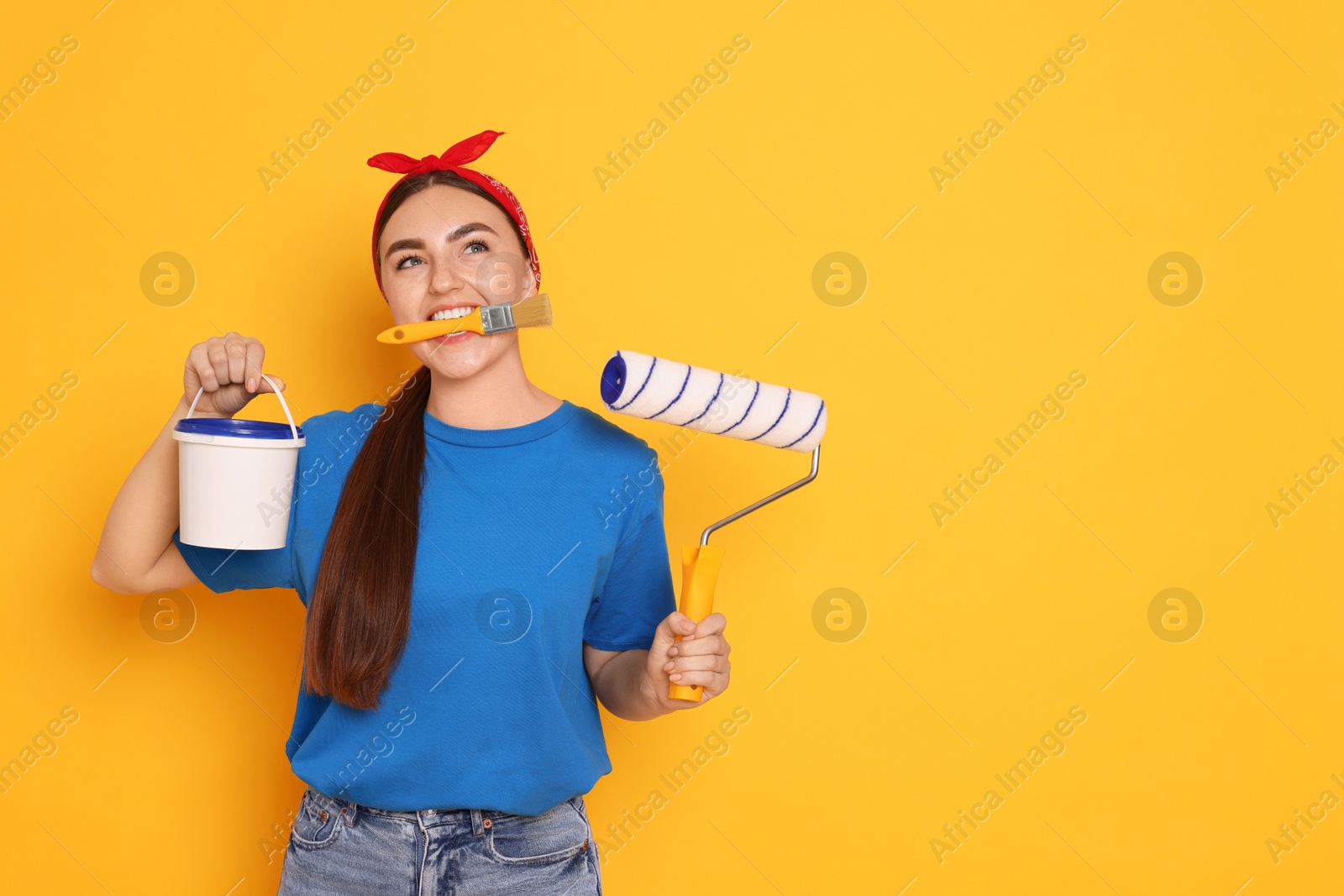 Photo of Portrait of young decorator with different tools on orange background, space for text