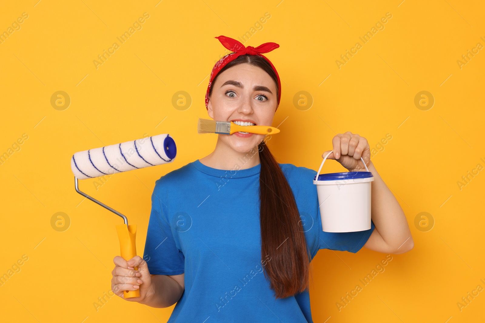 Photo of Portrait of young decorator with different tools on orange background