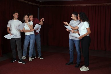 Photo of Professional actors with their scripts rehearsing in theatre