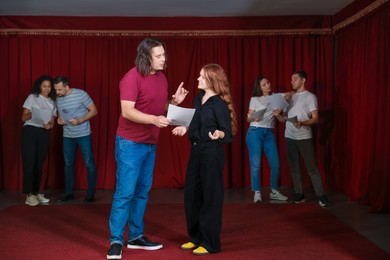 Professional actors with their scripts rehearsing in theatre