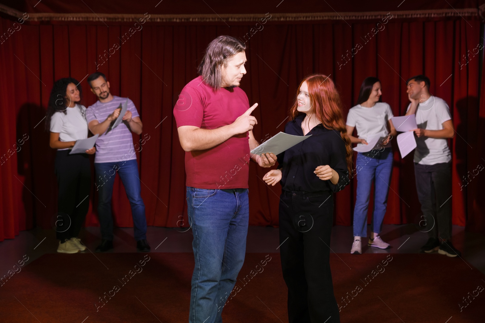 Photo of Professional actors with their scripts rehearsing in theatre