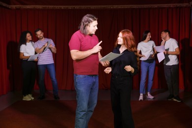 Professional actors with their scripts rehearsing in theatre