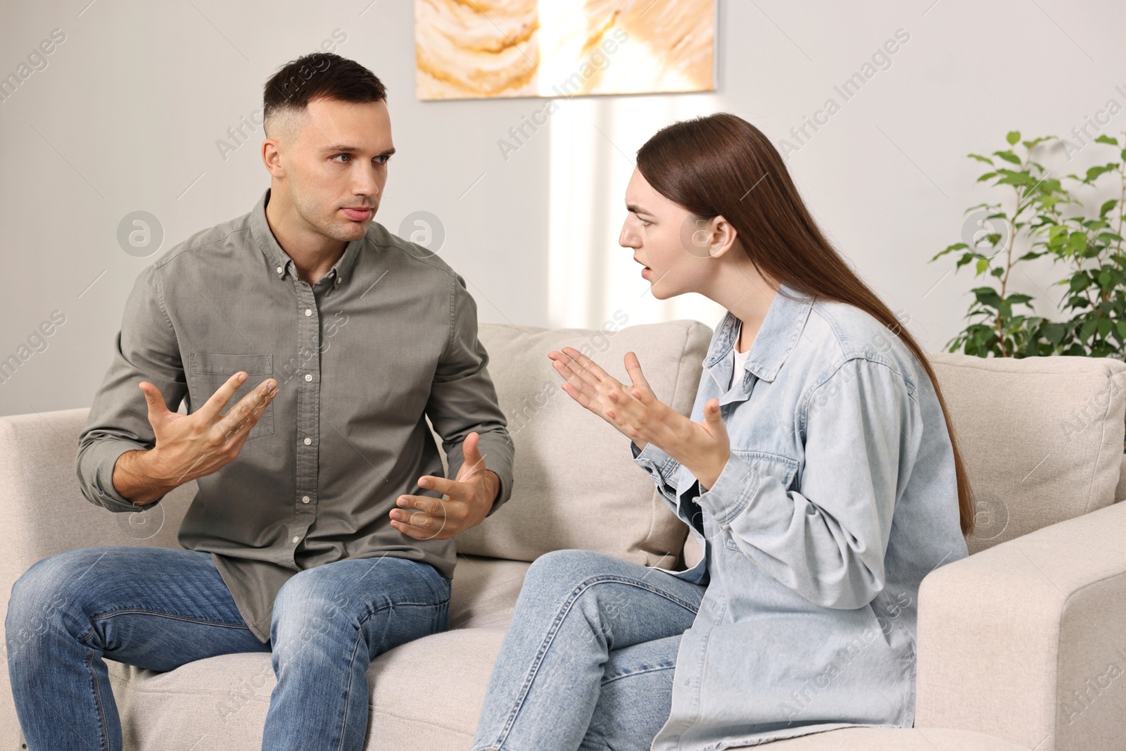 Photo of Young couple arguing on sofa at home