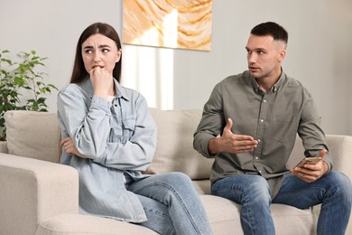 Photo of Husband showing smartphone with proofs to his unfaithful wife at home