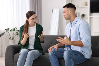 Photo of Young couple arguing on sofa at home