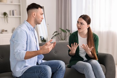 Photo of Young couple arguing on sofa at home