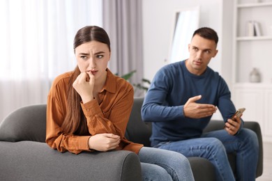 Photo of Upset woman ignoring her husband at home, selective focus