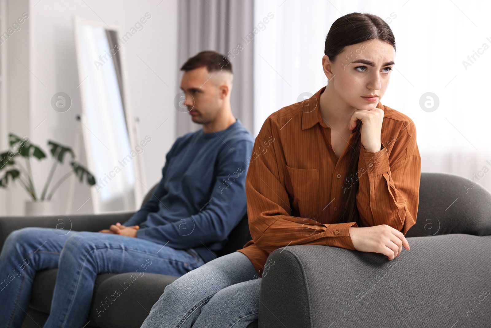 Photo of Offended couple ignoring each other at home, selective focus