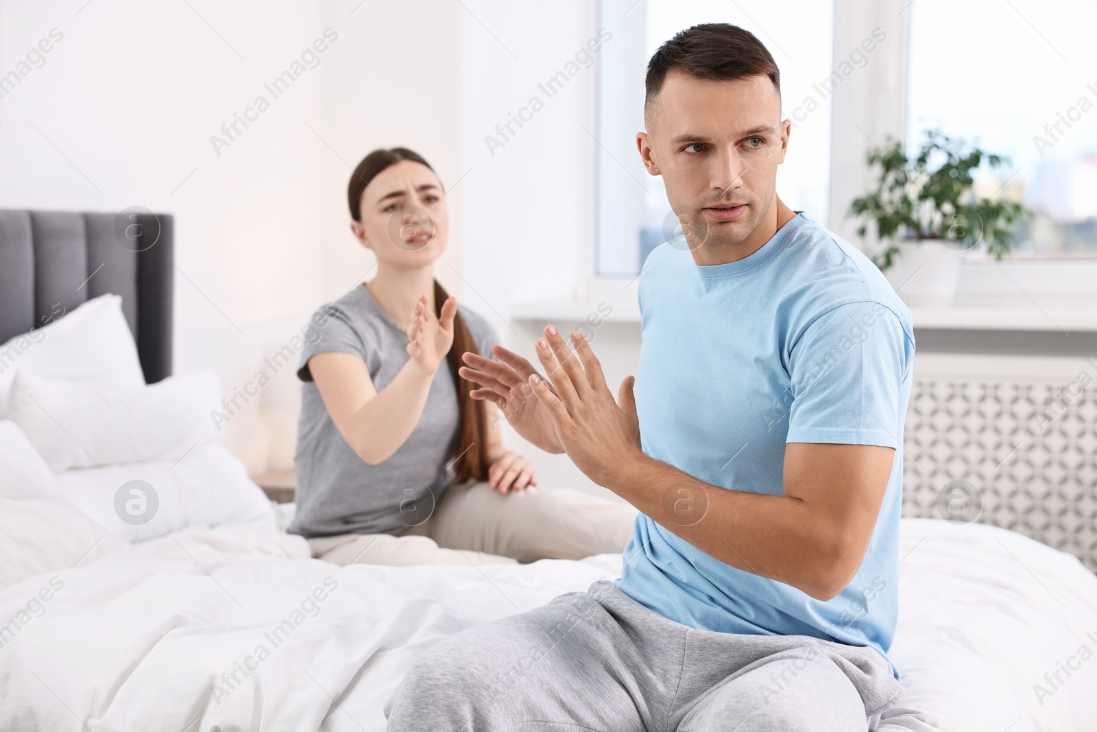 Photo of Wife apologizing her husband while he stopping her in bedroom, selective focus