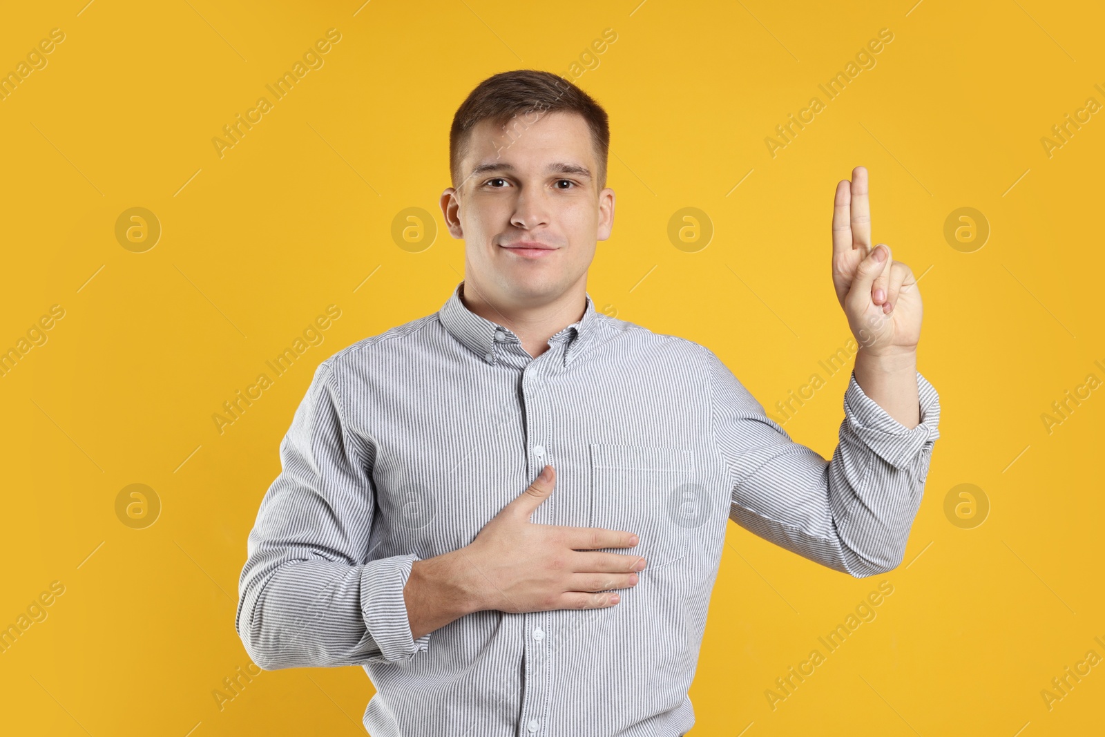 Photo of Man showing oath gesture on orange background. Making promise