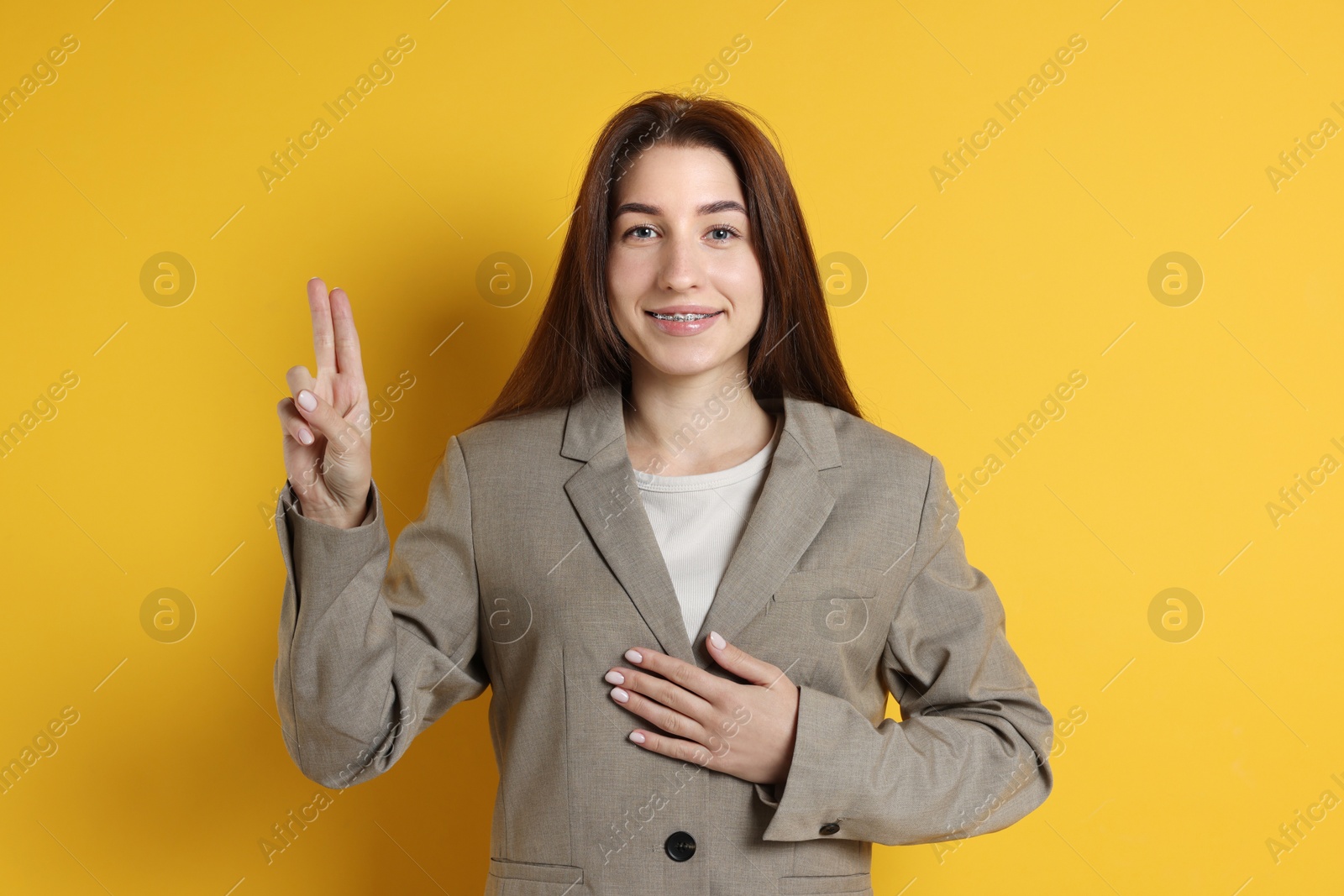 Photo of Woman showing oath gesture on orange background. Making promise