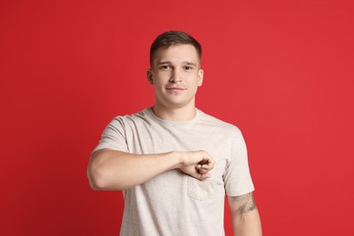 Photo of Man making promise on red background. Oath gesture