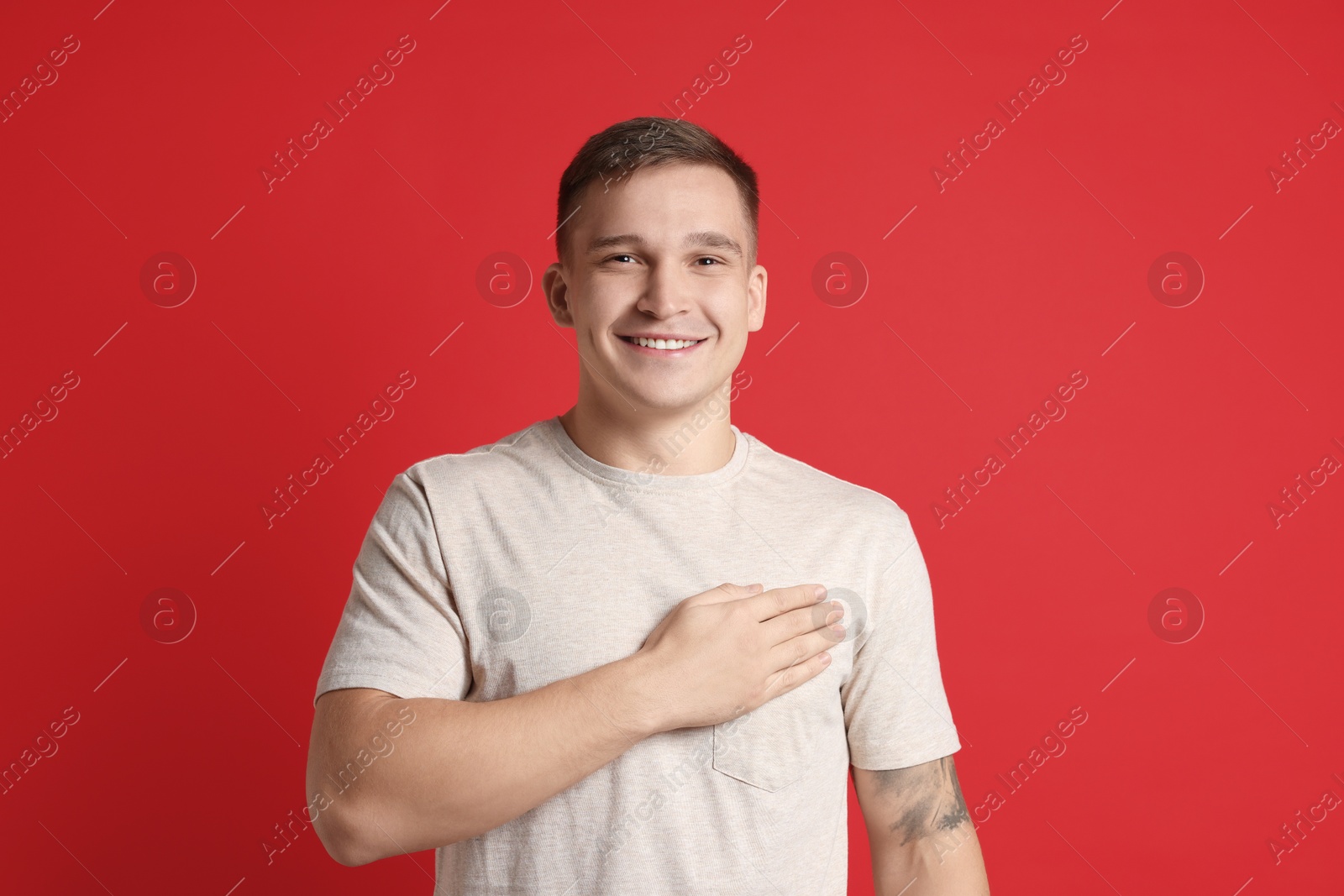 Photo of Man making promise on red background. Oath gesture