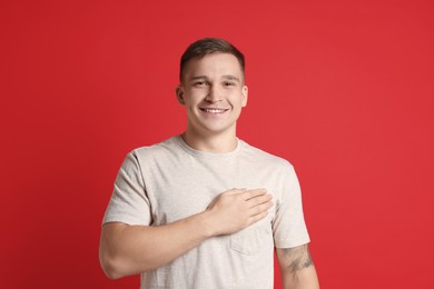 Photo of Man making promise on red background. Oath gesture