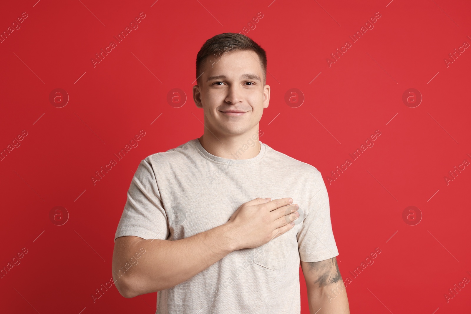 Photo of Man making promise on red background. Oath gesture