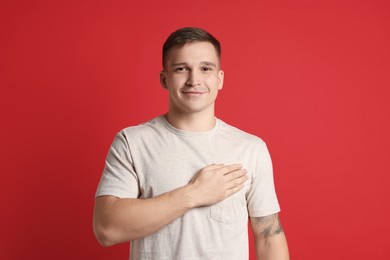 Photo of Man making promise on red background. Oath gesture