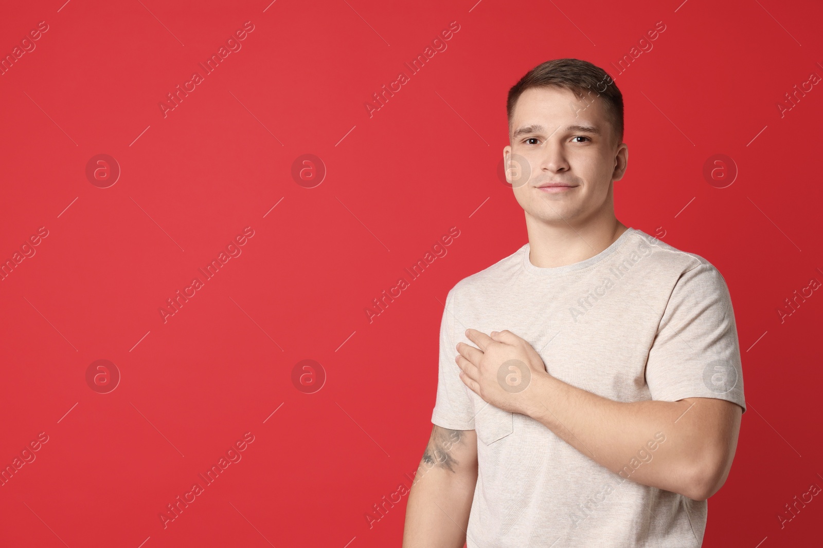 Photo of Man making promise on red background, space for text. Oath gesture