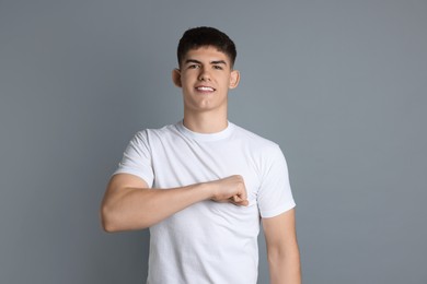 Photo of Man making promise on grey background. Oath gesture