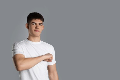 Photo of Man making promise on grey background, space for text. Oath gesture