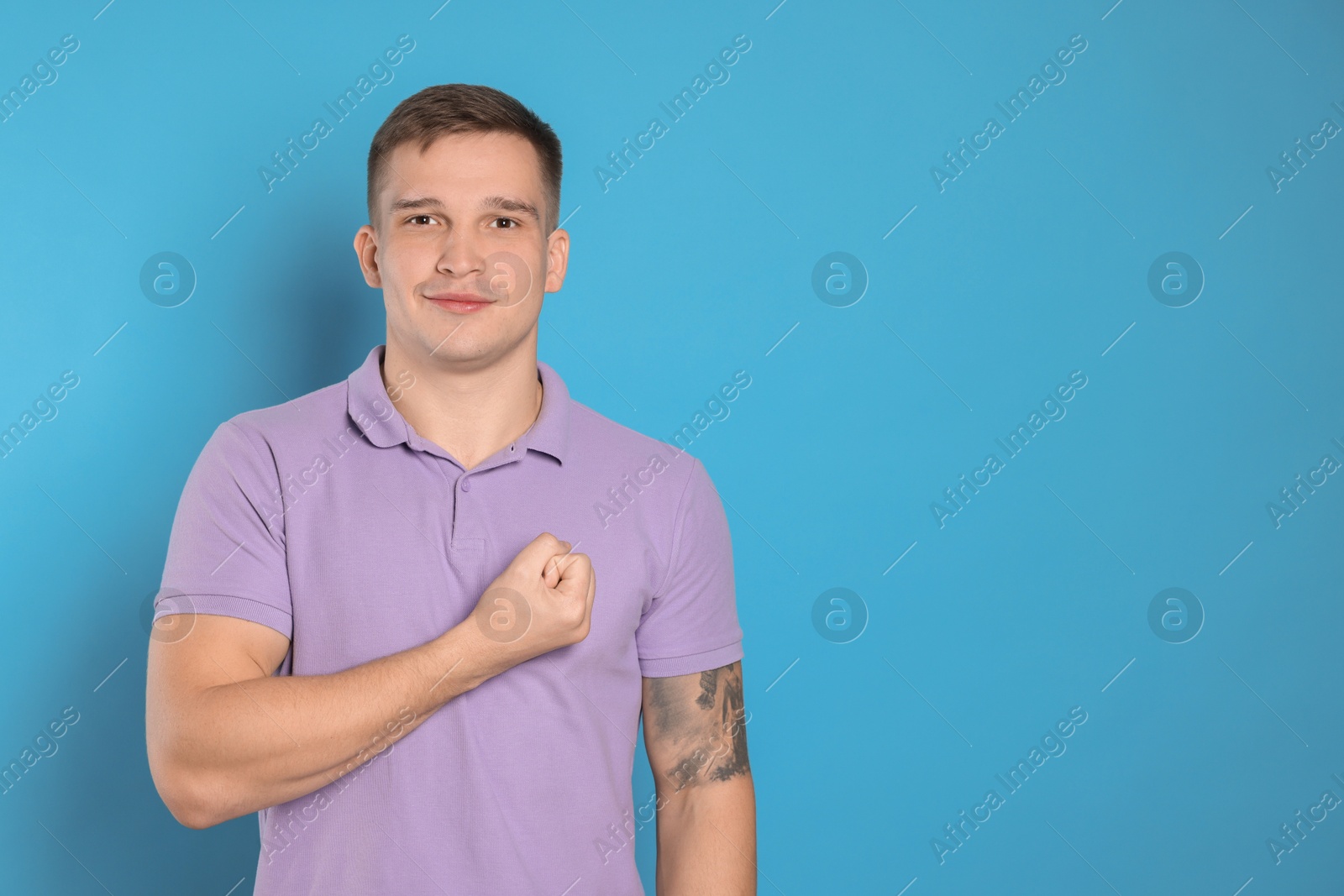 Photo of Man making promise on light blue background, space for text. Oath gesture