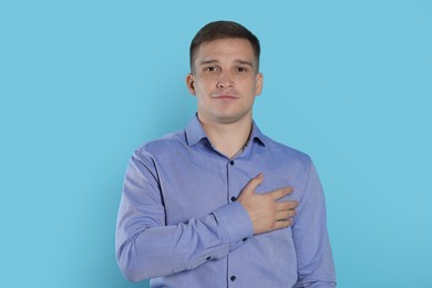 Photo of Man making promise on light blue background. Oath gesture