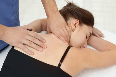 Photo of Osteopath massaging woman's back on couch indoors, closeup. Manual therapy