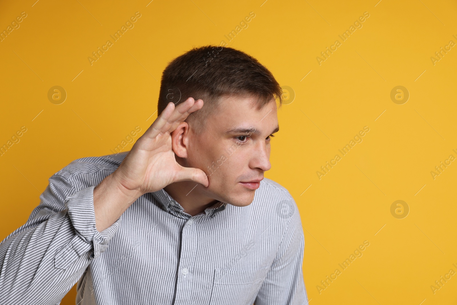 Photo of Man showing hand to ear gesture on orange background, space for text