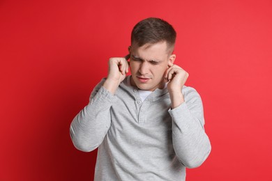 Photo of Man covering his ears with fingers on red background