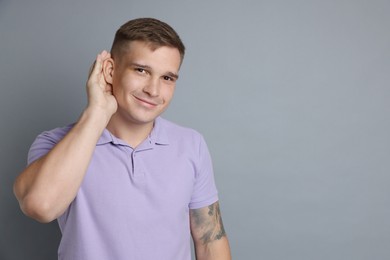 Photo of Man showing hand to ear gesture on gray background, space for text