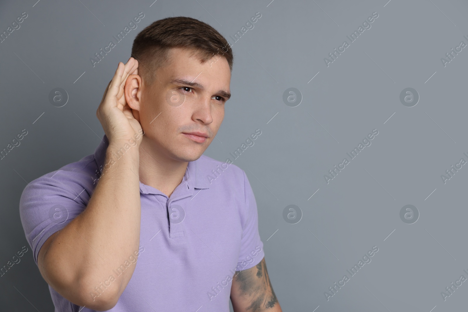 Photo of Man showing hand to ear gesture on gray background, space for text