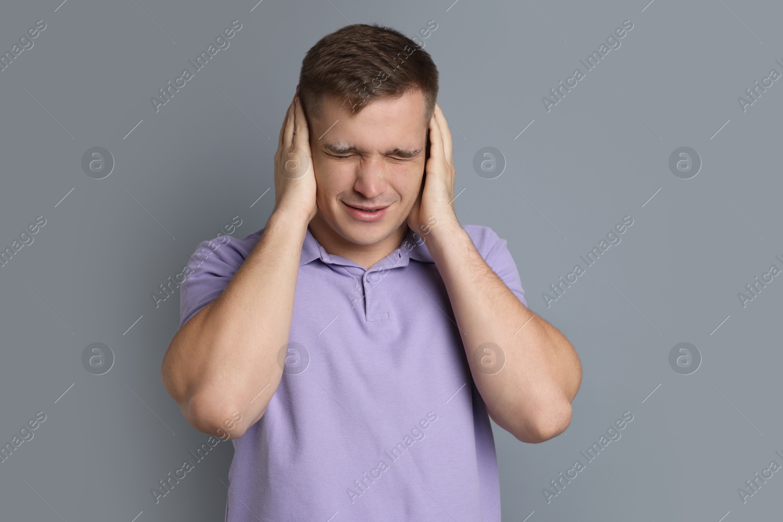 Photo of Man covering his ears on gray background