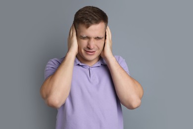 Photo of Man covering his ears on gray background