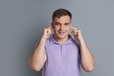 Photo of Man covering his ears with fingers on gray background