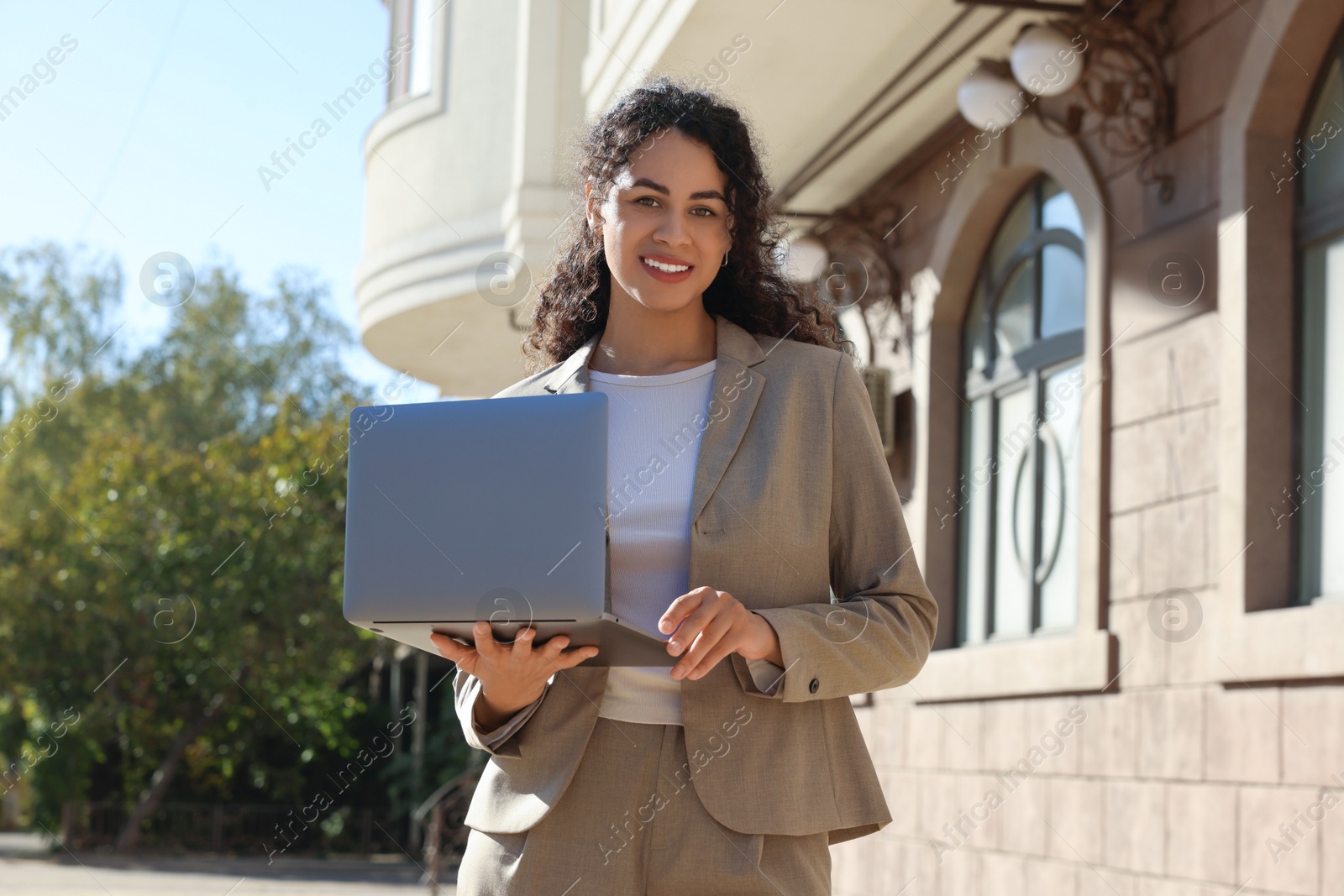 Photo of Portrait of young woman with laptop wearing stylish suit outdoors