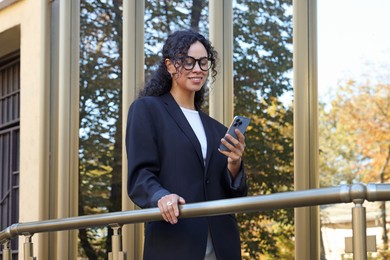 Photo of Portrait of young woman with phone wearing stylish suit outdoors