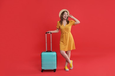 Photo of Happy traveller with suitcase on red background