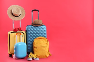 Photo of Travel abroad. Suitcases, backpack, hats and shoes on red background. Space for text