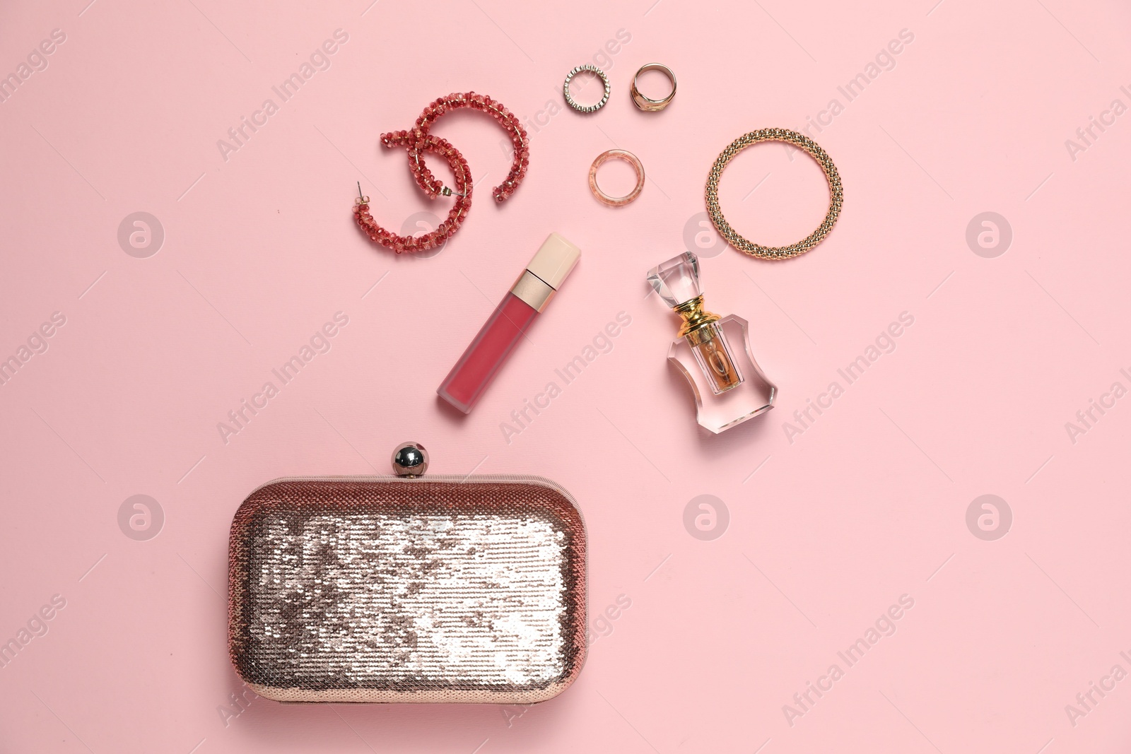 Photo of Many stylish jewelry, perfume and accessories on pink background, flat lay