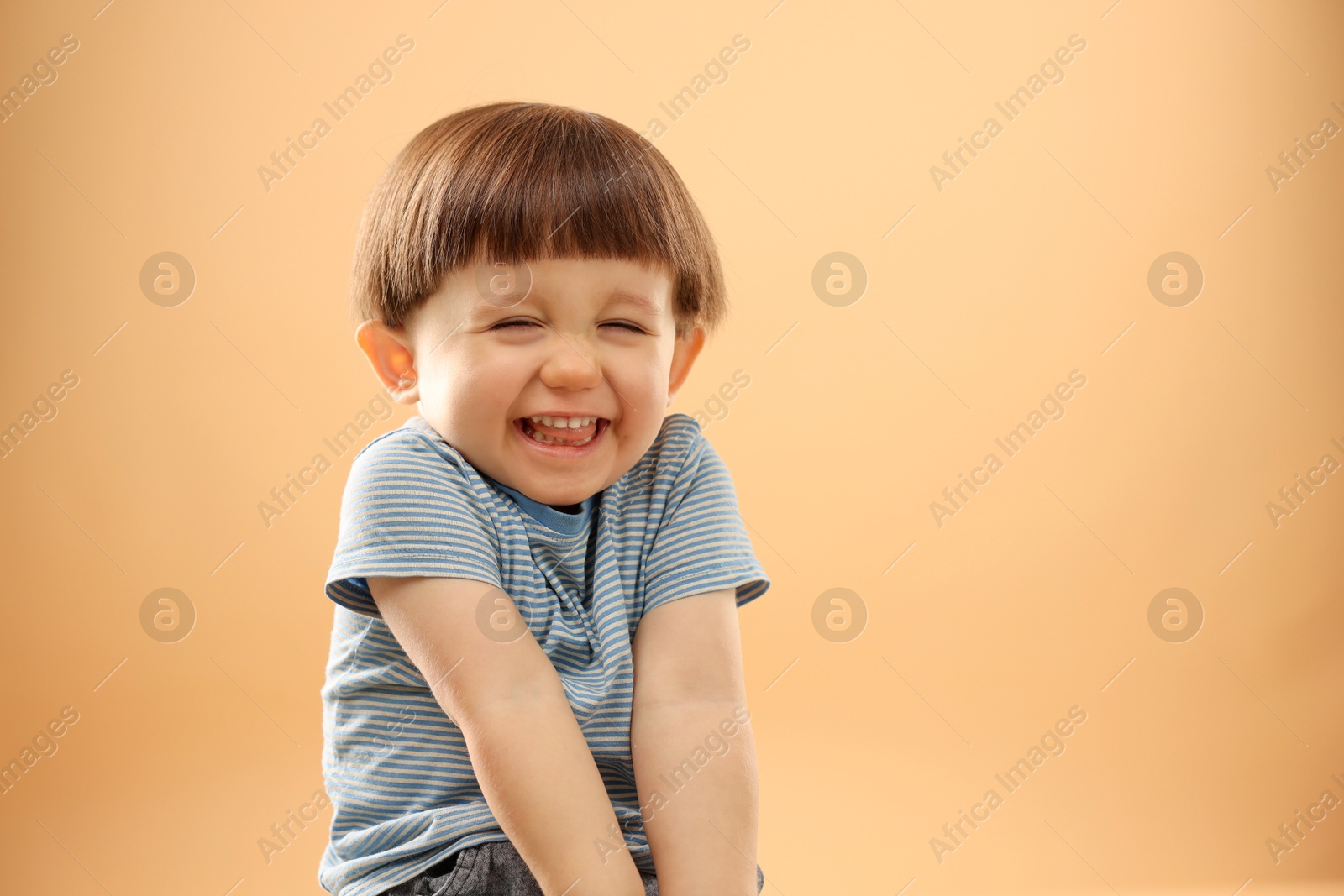 Photo of Portrait of happy little boy on beige background. Space for text