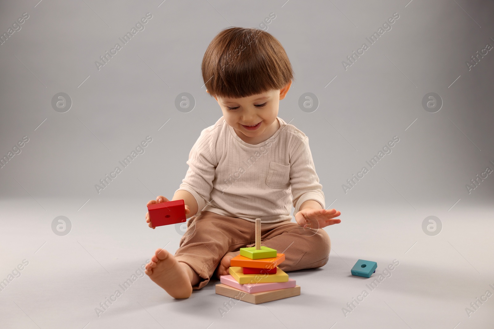 Photo of Cute little boy playing on grey background