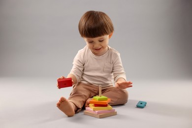 Photo of Cute little boy playing on grey background