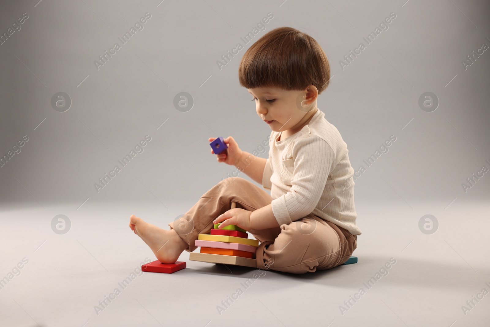 Photo of Cute little boy playing on grey background